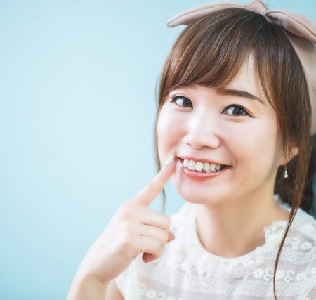 歯を指でさして微笑む女性